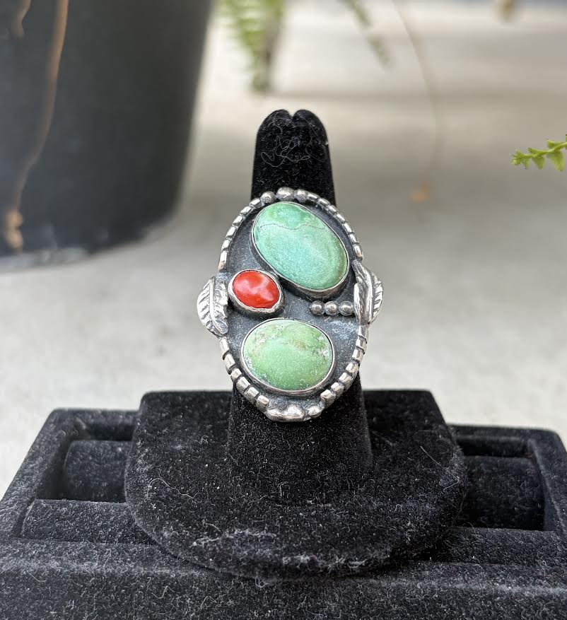 A silver ring with two oval turquoise stones and one small round coral stone