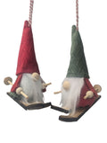 Two gnome ornaments on skis with red and green hats against a white background